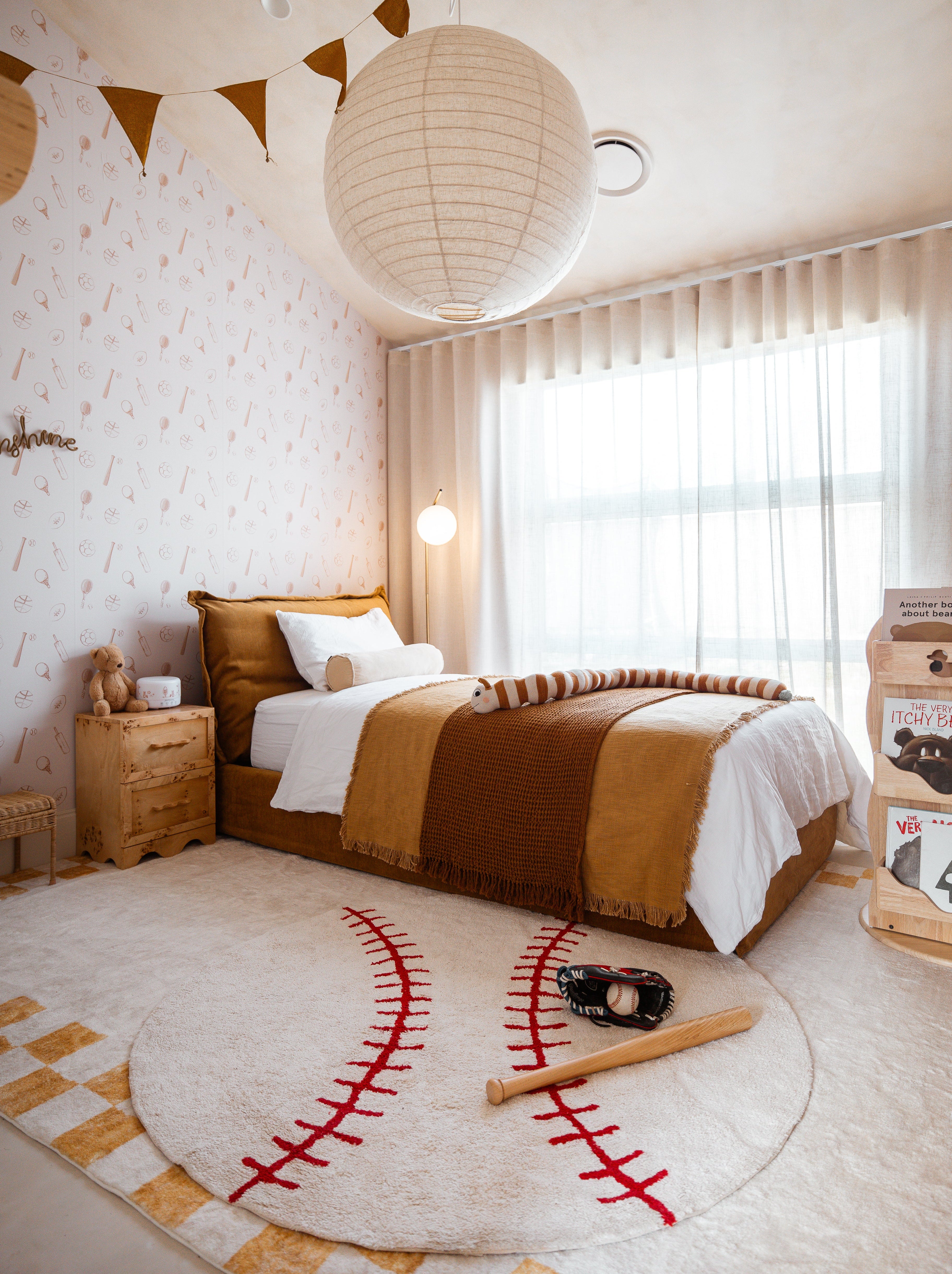 Children's bedroom with a bed, baseball rug, and decorative elements.