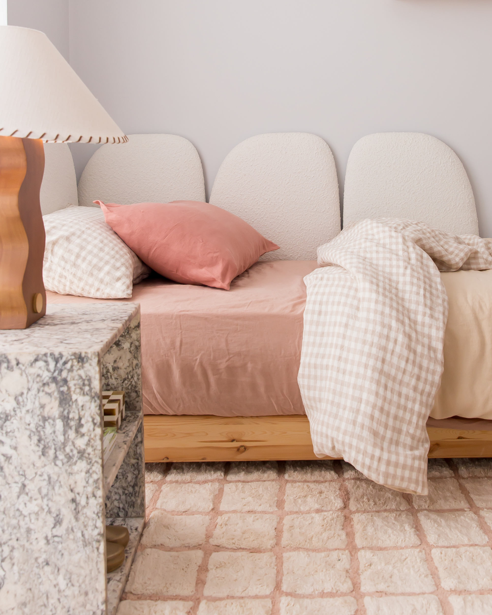 Neatly made bed with pink bedding and decorative pillows in a bedroom setting.
